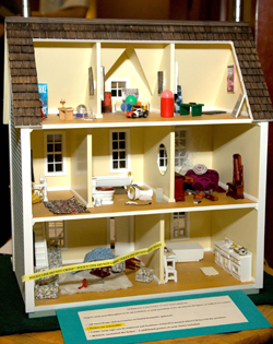 A doll’s house done up as a crime scene, complete with miniature crime scene tape.