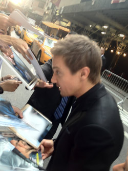 Jeremy Renner signs magazines and pictures for fans outside of Ziegfeld Theater in New York City on Monday, July 30.